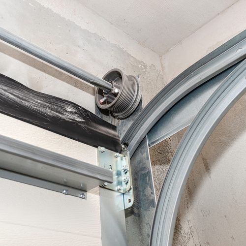 Guiding rails for a home garage door and steel rope drums, view from the inside.