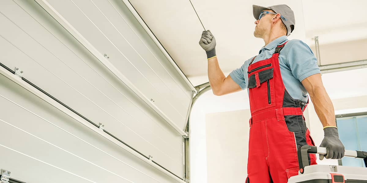 tech with red overall working on a garaeg door