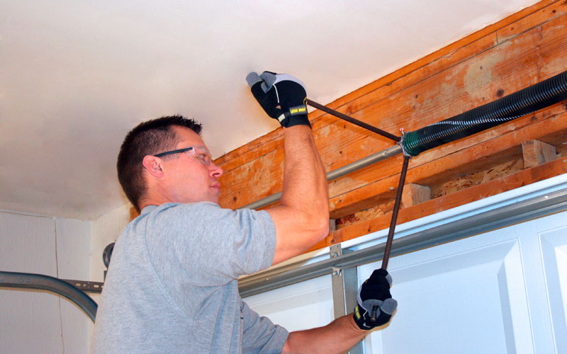 techincian winding a torsion spring on a garage door
