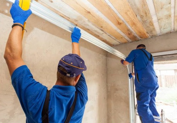 Technicians installing garage door tracks and hardware inside a garage