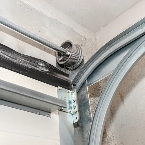 Guiding rails for a home garage door and steel rope drums, view from the inside.