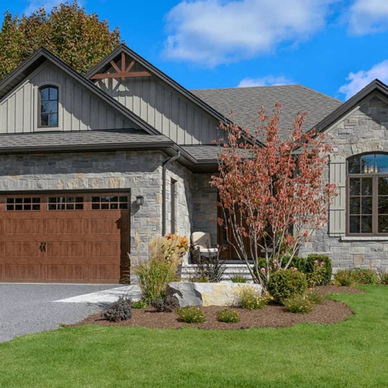 gray brick house with a walnut brown garage door