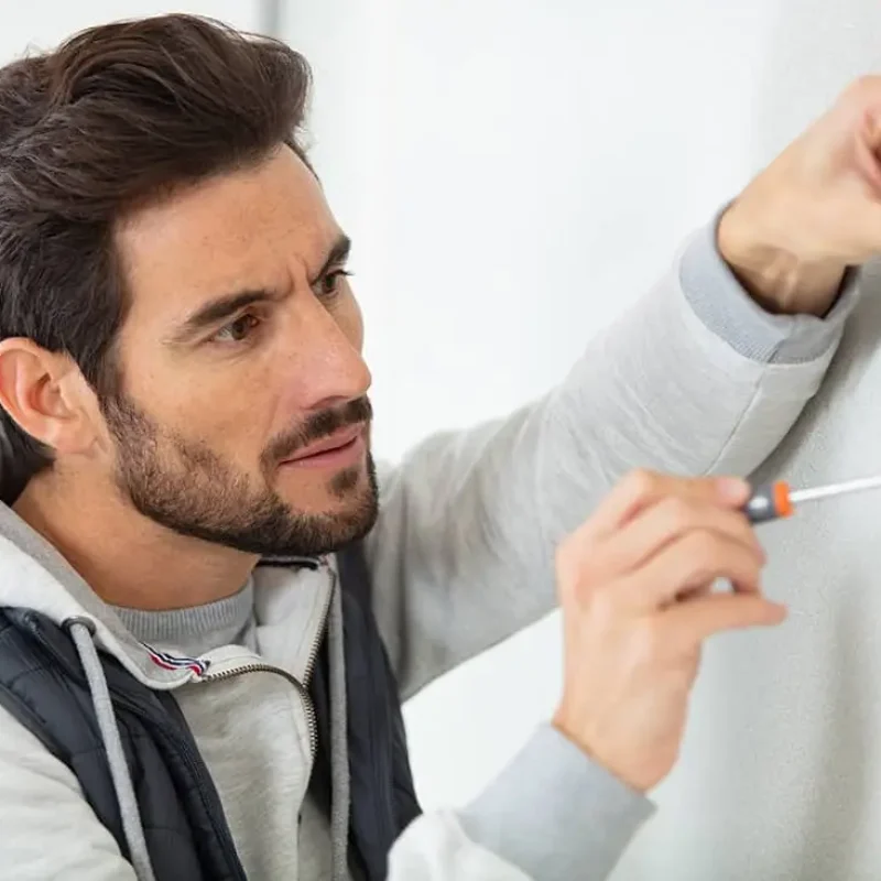 person using a screwdriver and holding a red strip