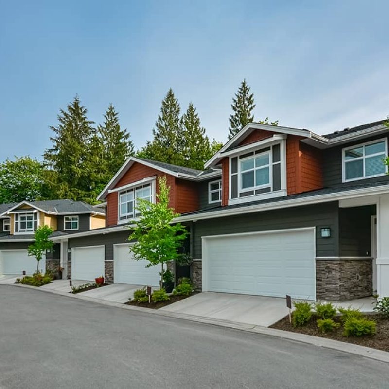 row of houses in a neighbordhood all sharing a white a garage door